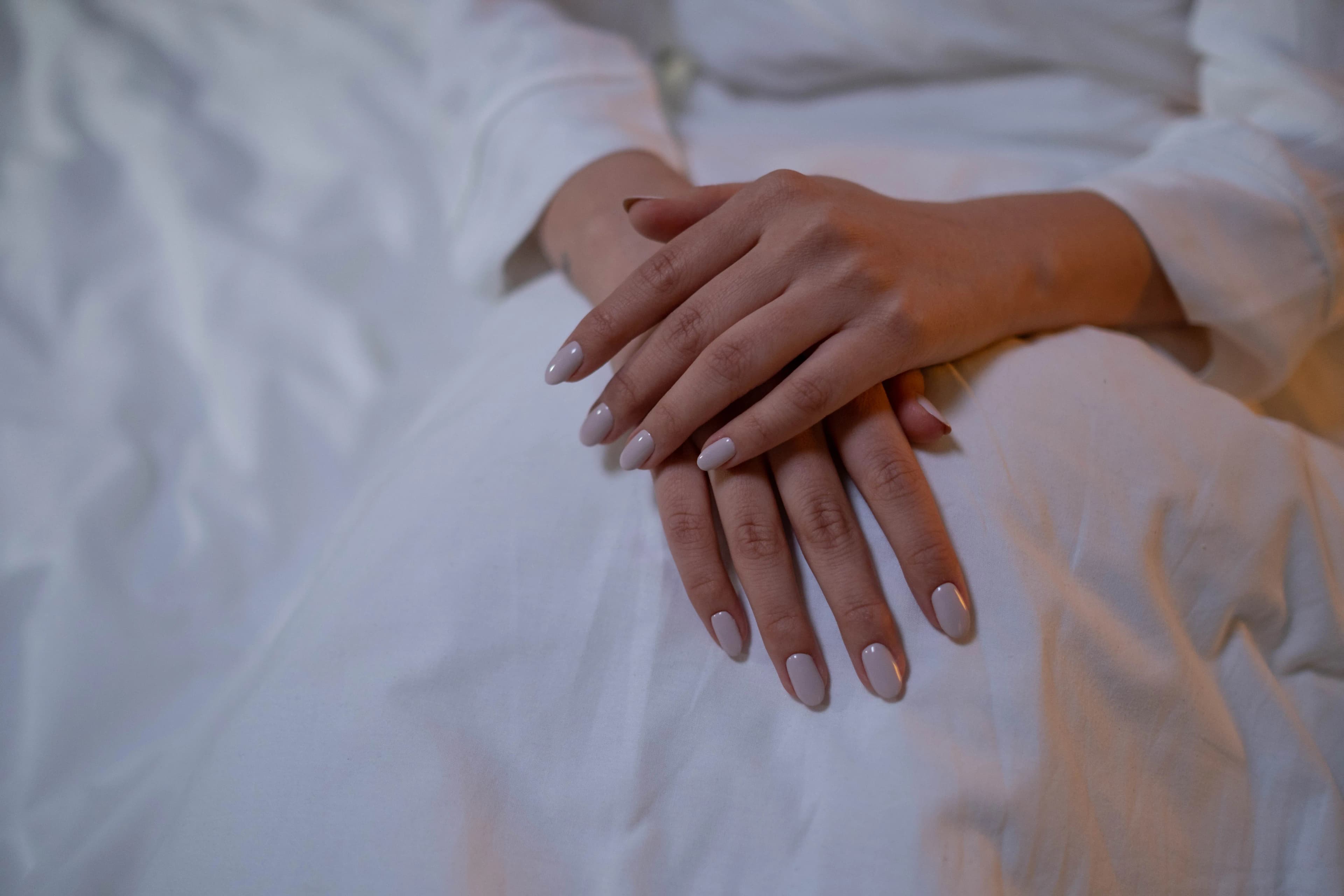Hands with nude nails on white fabric